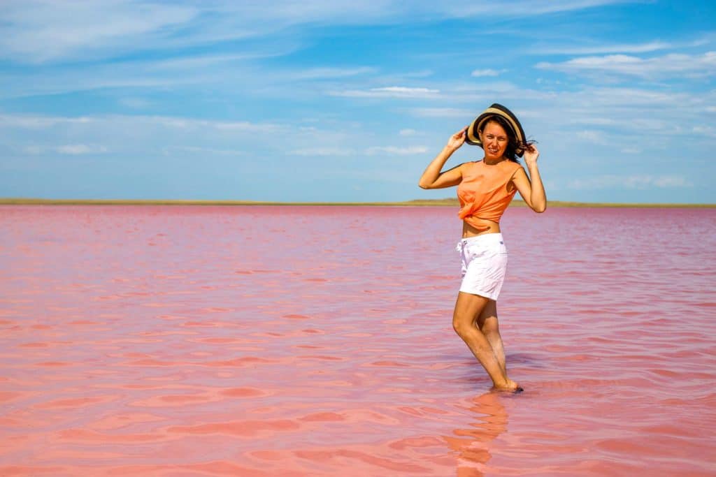 A woman posing standing in the pink lake Kobeytuz lake in Kazakhstan