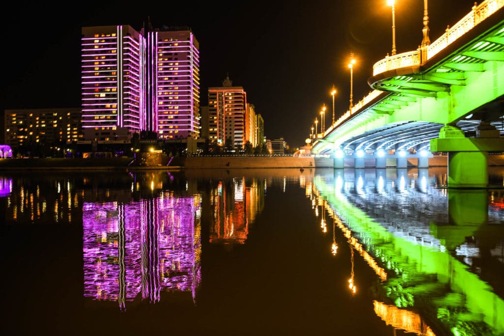 River in Nursultan with a lit bridge next to it