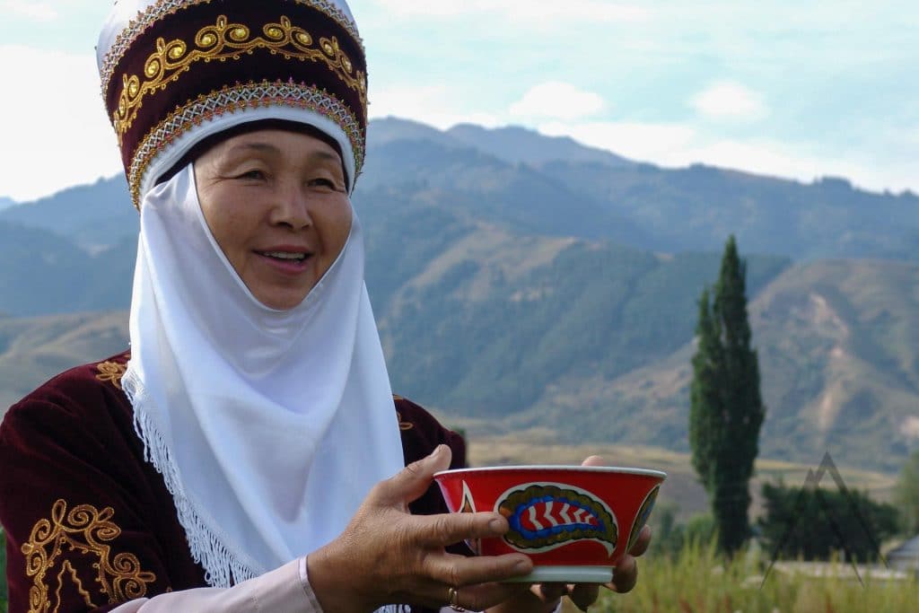 Kyrgyz woman wearing traditional clothes and serving kymyz