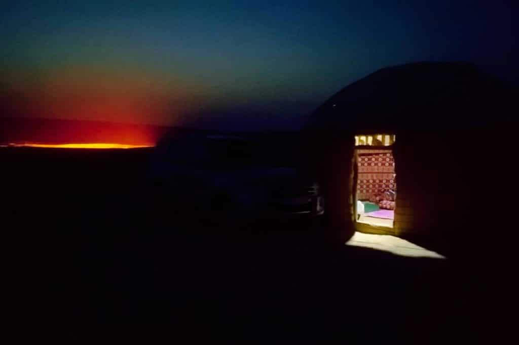 Darvaza crater at night next to a yurt