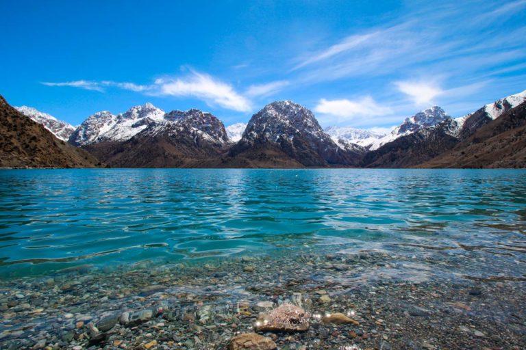 Iskander Kul stony beach and snow capped mountains