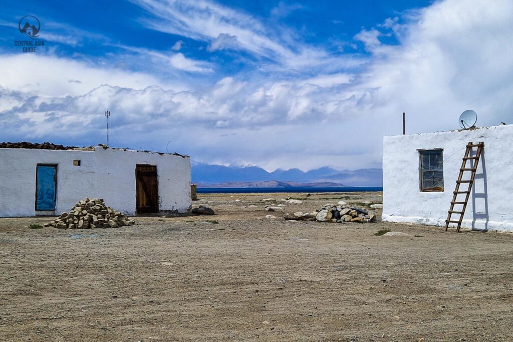 Karakol village in Pamirs with white washed houses and the lake appearing very dark blue in the background