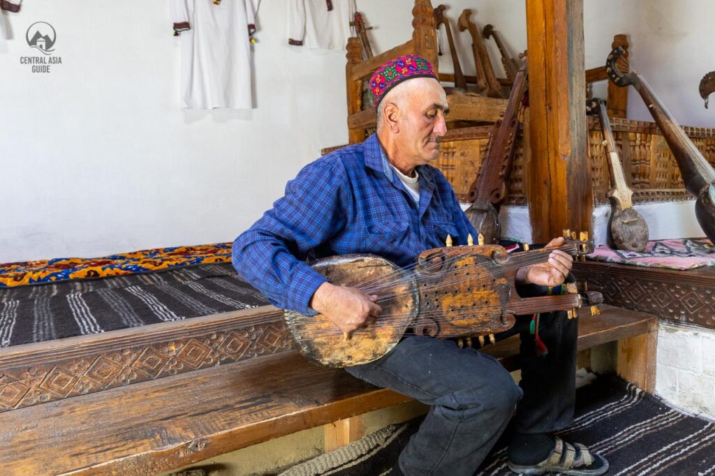 Pamiri man playing local instrument in a Pamiri house in Wakhan Valley