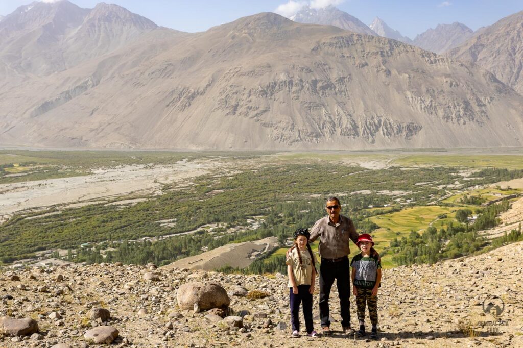 Guide and local children standing in Langar with a great view over the Wakhan Valley towards Afghanistan