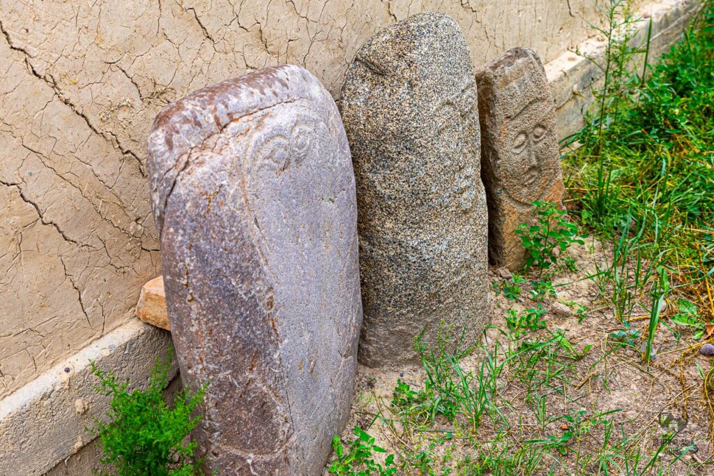 Balbals standing next to a museum wall near Kochkor